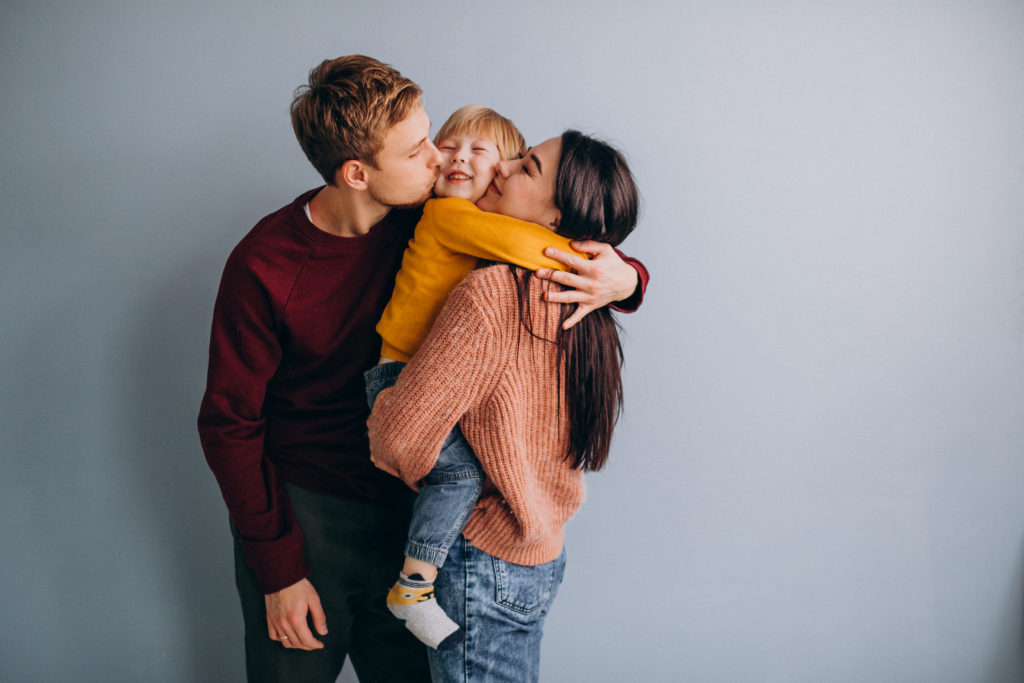 young family with little son together on grey background,representing parenting style